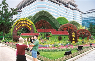 2021年6月，慶祝中國(guó)共產(chǎn)黨成立100周年主題花壇亮相長(zhǎng)安街沿線，西單東南角的全面小康主題花壇吸引市民駐足留影。 （圖片來(lái)源：人民視覺(jué)）